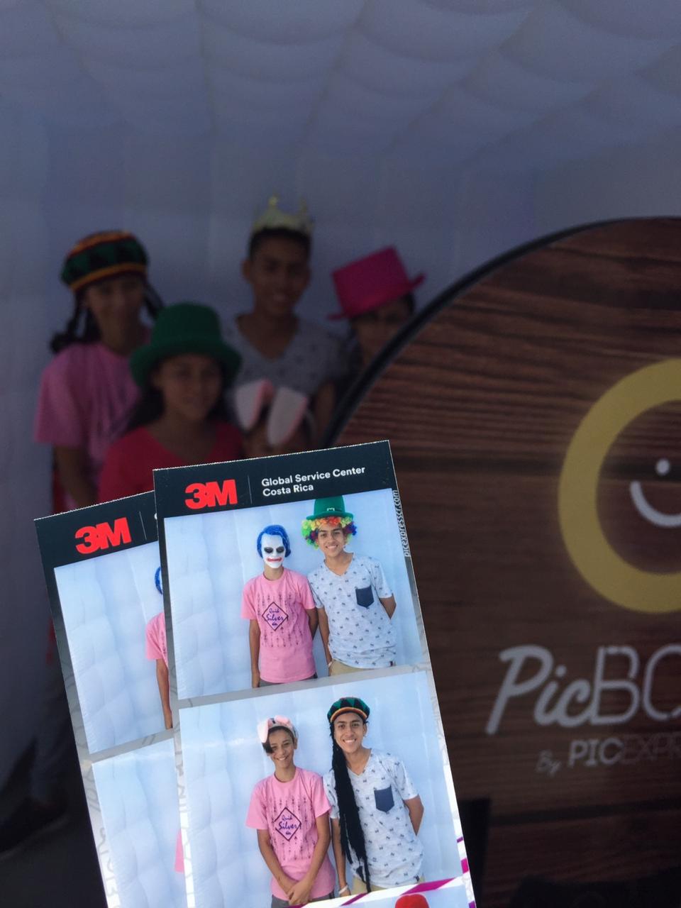Invitados sostienen tiras impresas frente a PicBox en un evento corporativo